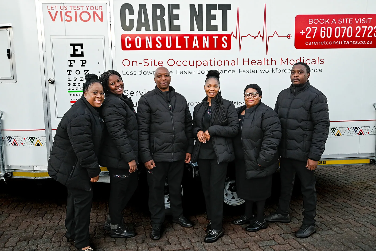 The Care Net clinical team standing beside a mobile occupational health clinic.